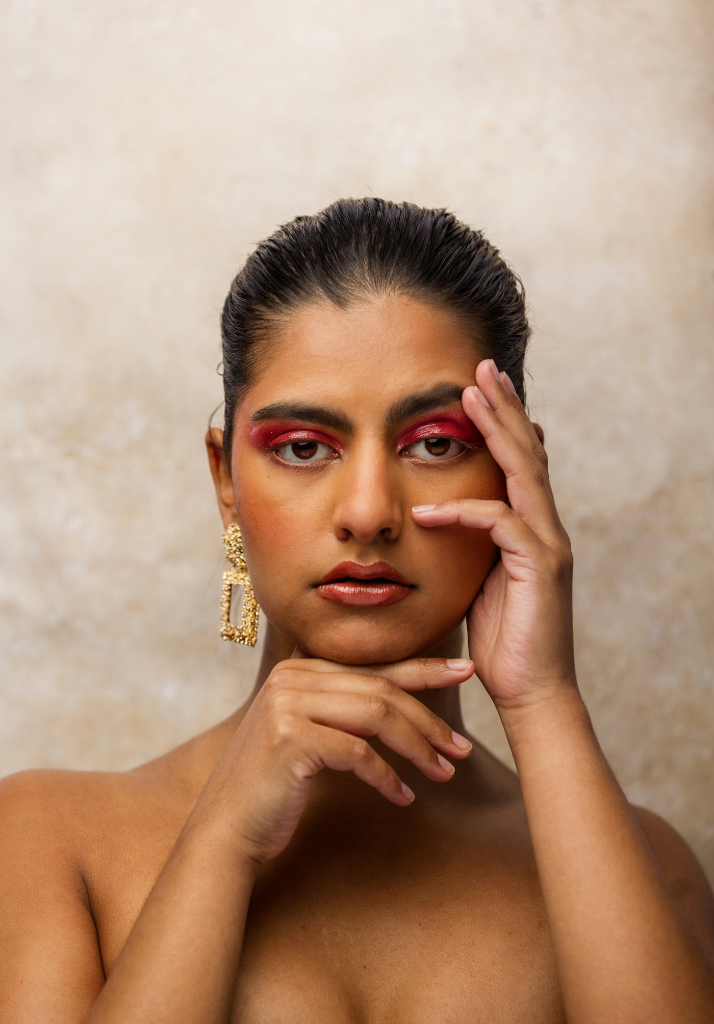 Woman with glowing skin, hands resting softly against her face